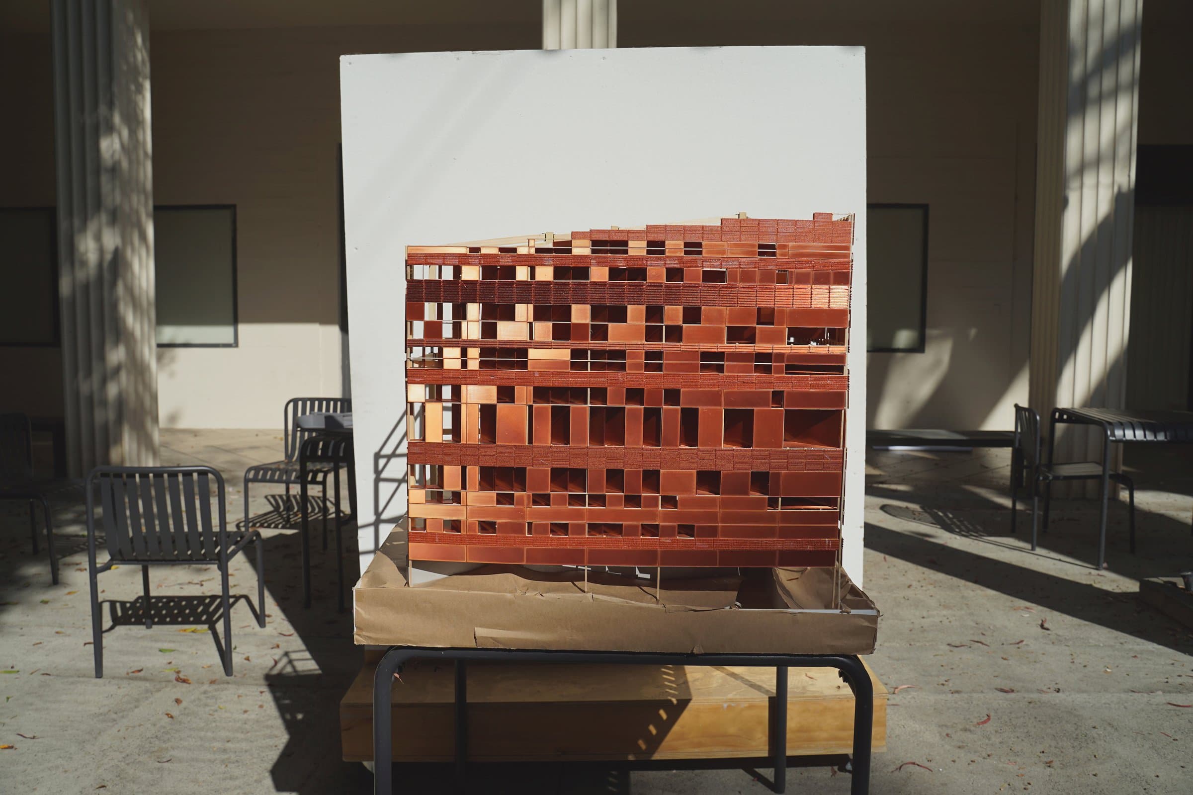 The model on a table in an outdoor courtyard, copper facade facing the camera.