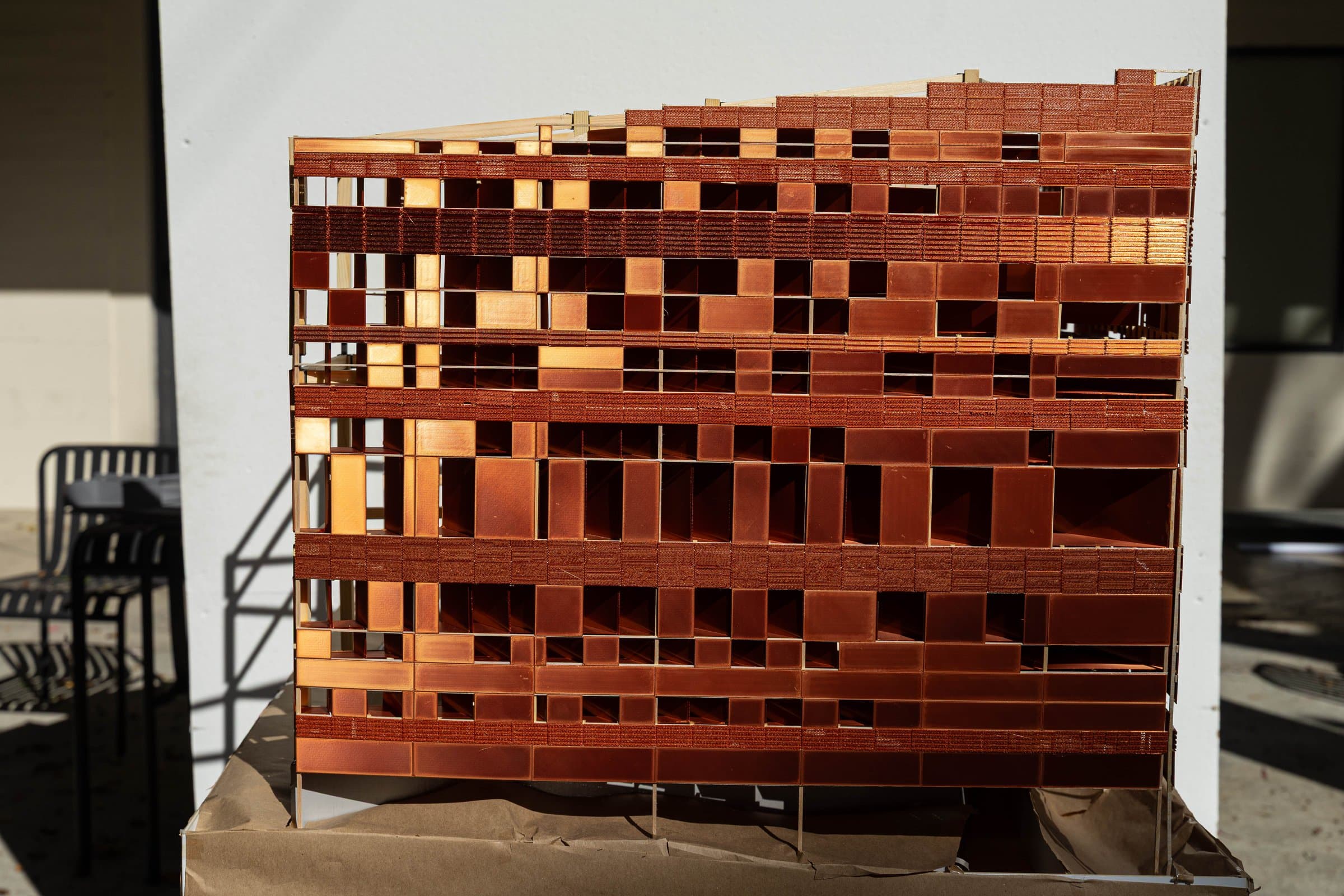 The copper facade in raking sun, panels and openings in detail.